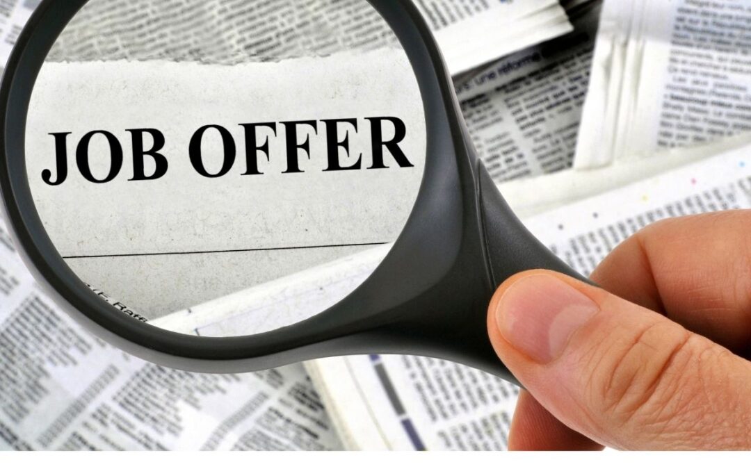 hand with a magnifier focused on the words Job Offer